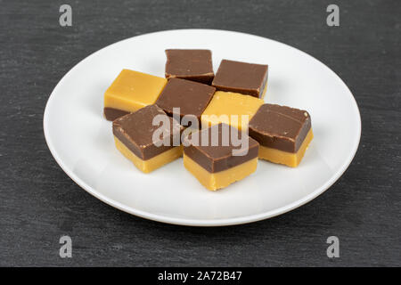 Gruppe der Acht ganze süsse braune Karamell Schokolade Süßigkeiten auf weißer Keramik Platte am grauen Stein Stockfoto