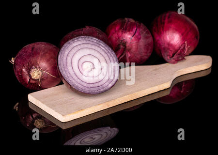 Gruppe von vier ganze die Hälfte der leckeren Zwiebel rot auf Holz Schneidebrett auf schwarzem Glas isoliert Stockfoto