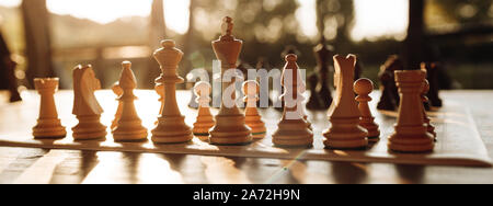 Schach Spielen auf einem Schachbrett bei Sonnenuntergang. Taktik und Strategie. Schwarze und weiße Zahlen. Stockfoto