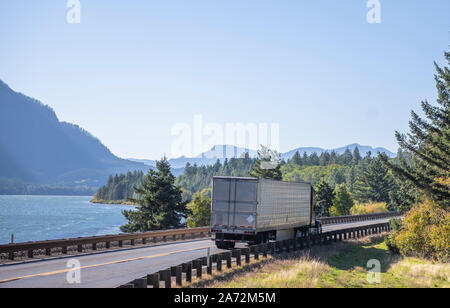 Big Rig Classic blau pro Amerikanische Motorhaube Semi Truck mit vertikalen Auspuffrohre Transport gefroren Cargo in gekühlten Auflieger, die auf dem Stockfoto