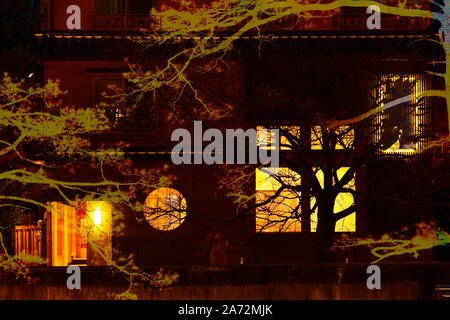 Geheimnisvollen Hintergrund mit grossen Bäumen und alten, dunklen Haus mit orange Licht eingerichtet. Halloween Hintergrund. Stockfoto