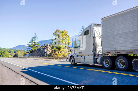 Big Rig Classic blau pro Amerikanische Motorhaube Semi Truck mit vertikalen Auspuffrohre Transport gefroren Cargo in gekühlten Auflieger, die auf dem Stockfoto