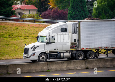 Big Rig classic Weiß pro Amerikanische Motorhaube Semi Truck mit Kühlschrank für den Transport von gefrorenen Fracht in gekühlten Auflieger auf dem moun Stockfoto