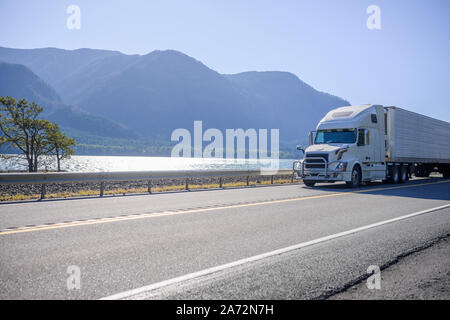 Big Rig classic Weiß pro Amerikanische Motorhaube Semi Truck mit Kühlschrank für den Transport von gefrorenen Fracht in gekühlten Auflieger auf dem moun Stockfoto