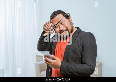 Stress Geschäftsmann sein Telefon Holding im Büro Stockfoto