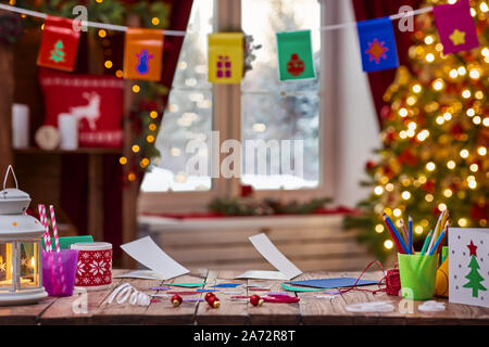 Frohe Weihnachten und schöne Feiertage. Schreibtisch aus Holz mit Karten, Geschenke und Dekorationen für den Urlaub. Weihnachten Kreativität. Ein schönes Wohnzimmer Einrichtung Stockfoto