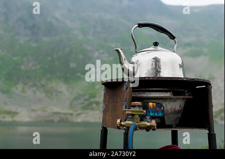 Tourismus, einem alten Wasserkocher ist auf einem rostigen Gasbrenner erhitzt Stockfoto