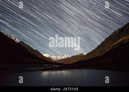 Tolle Nacht mit Sternen in Form von Spuren über die verschneiten Berge, Gletscher und den See im Herbst. Altai, Russland Stockfoto