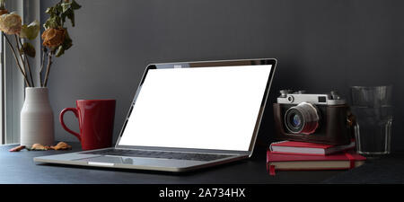 Dunkle trendy Arbeitsbereich mit Laptop und Kamera auf Schwarz und Dunkelgrau Wand mit Büromaterial Stockfoto