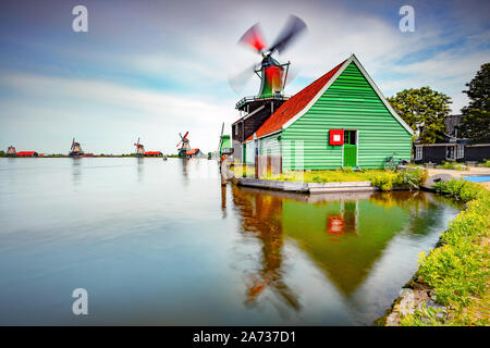 Schöne bunte Windmühlen am Ufer eines Flusses, die traditionelle Ansicht der Niederländischen Landschaft, Zaanse Schans Stockfoto