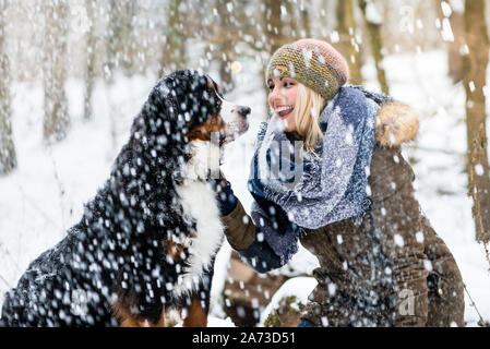 Frau zu ihrem Hund im Winter und den Schnee gemeinsam entdecken Stockfoto