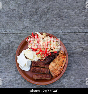 Gesunde, leckere und starke Gericht, Hühnchen Steak und Leber, Cevapcici, Milchprodukte und Salat in Braun Keramikplatte auf alten Eiche Tabelle, Ansicht von oben Stockfoto