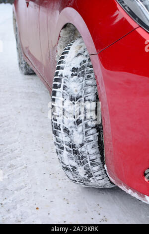 Winter Reifen voller Schnee, rotes Auto und leere Landstraße durch frischen Schnee bedeckt, winter Fahrbedingungen Stockfoto