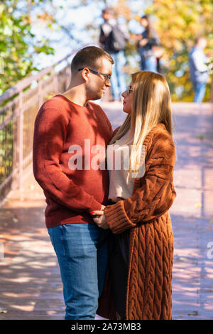 Junges Paar in der Liebe, im Freien in einem Herbst Park steht auf einer Brücke halten sich an den Händen und zärtlich an jedem anderen Suchen Stockfoto