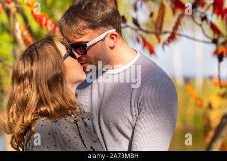 Romantische junge coupé Küssen in der Garten im Herbst gegen einen farbigen Hintergrund von Herbstlaub Stockfoto