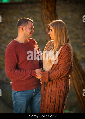 Junges Paar in Liebe zärtlich an einander suchen, wie Sie halten sich an den Händen, im Freien in einem Garten oder Park im Herbst stehen Stockfoto