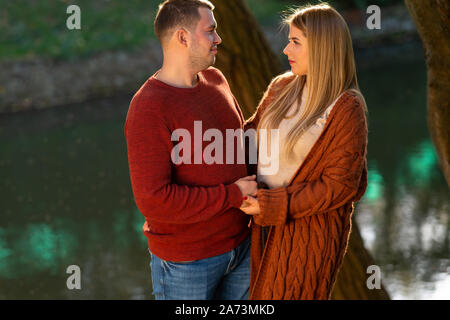 Liebevolle junge Paare halten sich an den Händen und starrte in die Augen in einem Panorama Format, im Freien in einem Park Stockfoto