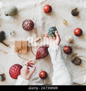Weihnachten Spielzeug und Weibes Hände mit Pine Cone, Quadrat Erntegut Stockfoto