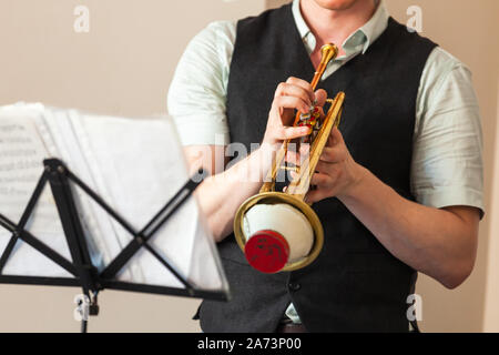 Live Musik im Hintergrund. Trompete mit geraden Mute in trompeter Hände. Nahaufnahme Foto mit selektiven Fokus Stockfoto