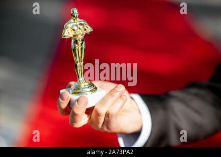 Mann mit berühmten Film Award Statue auf dem roten Teppich Hintergrund, Nahaufnahme Stockfoto