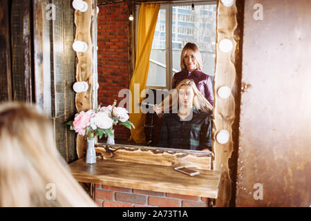 Schöne Frau sitzt vor dem Spiegel im Friseursalon. Friseur ist mit der Gesundheit Haar Ihrer Kunden unzufrieden. Probleme mit Haar. Haarpflege, werden Stockfoto