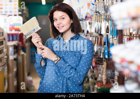 Happy girl Entscheiden auf Pinsel für die Dekoration Haus in Farbe liefert Store Stockfoto