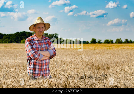 Gerne suchen Bauer im Stroh Hut steht bei der Ernte bereit Weizenfeld Stockfoto