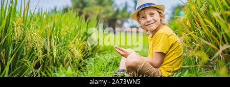 Junge spielt Telefon sitzen auf dem grünen Gras, moderne Kinder, neue Technologien, die Abhängigkeit der Kinder auf dem Handy Banner, LANGE FORMAT Stockfoto