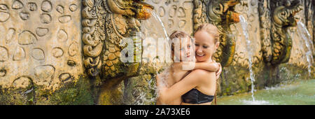 Mutter und Sohn Reisende in heißen Quellen von Banjar. Das Thermalwasser wird aus dem Mund von Statuen an einem heißen Quellen von Banjar, Bali, Indonesien freigegeben Stockfoto