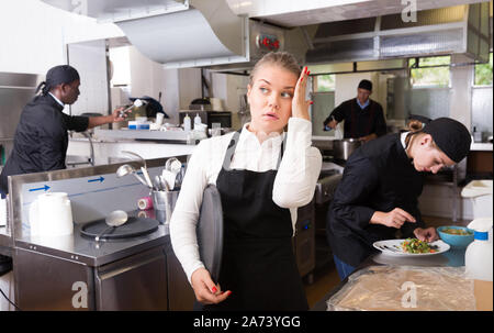 Unglücklich und müde junge Kellnerin warten bestellten Gerichte im Restaurant Küche Stockfoto