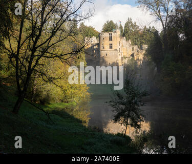 Alte Schloss von Beaufort in Luxemburg von der Seite der Teich auf der nebligen Morgen mit Baum Silhouette gesehen Stockfoto