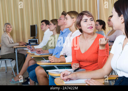 Junge Schülerin lebhaften Gespräch mit Ihr groupmates während des Unterrichts im Hörsaal Stockfoto
