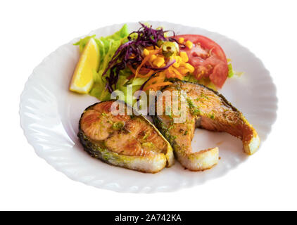 Lecker gebratene Lachssteaks mit frischem Salat und Zitrone. Auf weissem Hintergrund Stockfoto