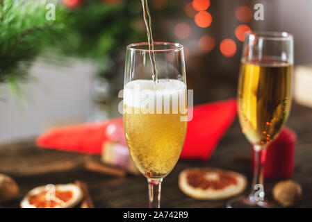 Sekt Champagner gießt in einem Glas auf dem Hintergrund der bokeh Girlanden. Festliche Weihnachten Tabelle an Silvester Stockfoto