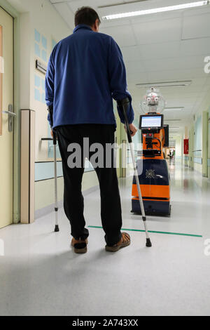 29. Oktober 2019, Thüringen Eisenberg: ein Patient Züge mit Hilfe von Ringo, ein Roboter, Wandern in einem Flur im Krankenhaus Waldkliniken Eisenberg. In einem dreijährigen Forschungsprojekt, der Einsatz von Robotern für Gang Übungen mit Patienten nach Hüftoperationen wurde entwickelt und getestet. Der Roboter arbeitet autonom und erkennt falsche Körperhaltungen, wie der Patient geht, korrigiert sie und lobt die Fortschritte. Die Studie zeigte, dass Patienten, die zusammen mit dem Roboter Zug schneller als diejenigen, die allein Zug gehen können. Nach Einschaetzung der Teilnehmer ist das Projekt ist einzigartig in Deutschland und international in der Medica Stockfoto