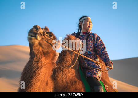 Frau in traditioneller mongolischer Kleidung mit Ihrem baktrischen Kamel. Die Gobi, Mongolei. Stockfoto