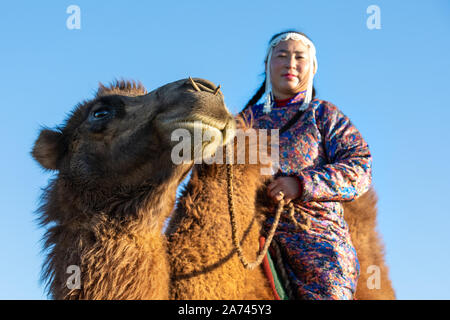 Frau in traditioneller mongolischer Kleidung mit Ihrem baktrischen Kamel. Die Gobi, Mongolei. Stockfoto