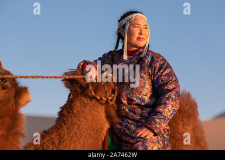 Frau in traditioneller mongolischer Kleidung mit Ihrem baktrischen Kamel. Die Gobi, Mongolei. Stockfoto