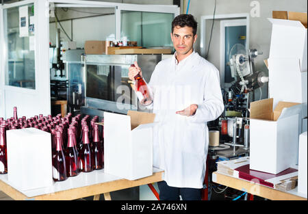 Fröhlicher mann Weingut Arbeiter in Uniform Verpackung Wein Flaschen auf dem Weingut Factory Stockfoto