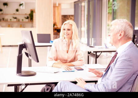 Der Anlageberater Geschäftsfrau im Büro Schreibtisch vor dem Computer sitzen und Consulting mit älteren Geschäftsmann über wachsendes Unternehmen. Stockfoto