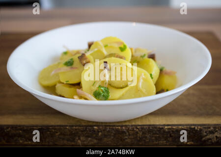 Essen Fotografie einer veganen deutschen Kartoffelsalat in einer weißen Schüssel Stockfoto