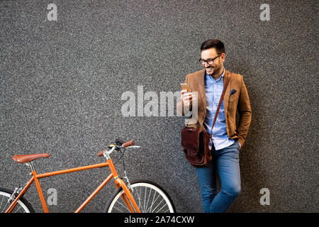 Gerne Unternehmer außerhalb der Bürozeiten in städtischen. Jungen kaukasischen Mann, Smartphone für Unternehmen arbeiten. Stockfoto