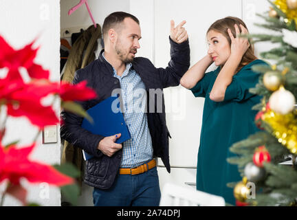 Verärgert junge Frau weigert zu Schulden Zahlung zu Schuldeneintreiber, die Ihr zu Hause besucht in der Weihnachtszeit Stockfoto