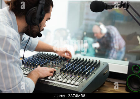 Professionelle effiziente positive Toningenieur Regulierung der Lautstärke mit Studio Mixer während live Radio Show Stockfoto