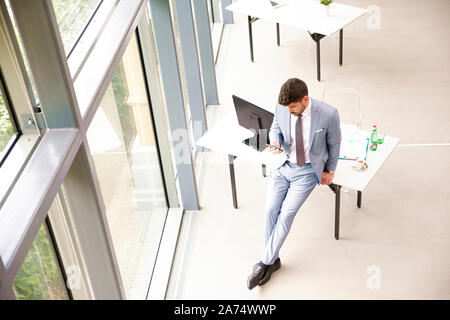 Hohen Winkel voller Länge geschossen von Geschäftsmann test Messaging im Büro stehen. Stockfoto