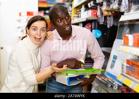 Junge froh, heiter Paar zeigt auf ein Regal mit Bürobedarf, Schreibwaren Shop beim Shoppen Stockfoto