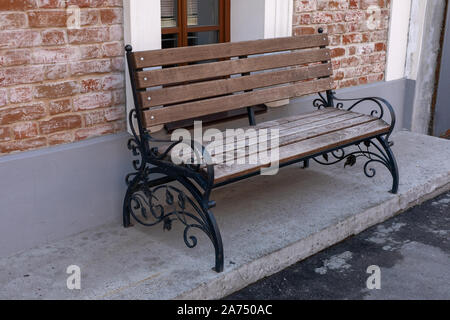 Textur Hintergrund städtische Landschaft Sitzbank mit schmiedeeisernen Beine. Holz Garten Bank, auf einer Straße der Stadt. Nahaufnahme einer Holzbank. Stockfoto