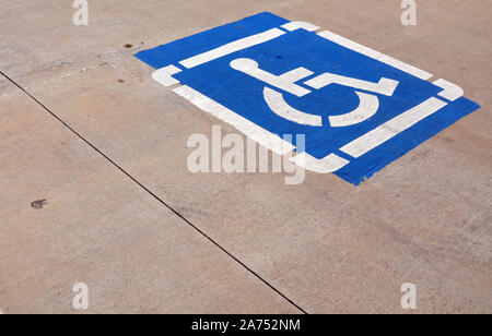 Eine blau-weiße Rollstuhl Zeichen gemalt auf einer konkreten Parkplatz Stockfoto