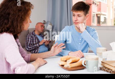 Stirnrunzelnd Teenager zu rügen Mutter zu Hause hören, Vater ruht auf einem Sofa Stockfoto