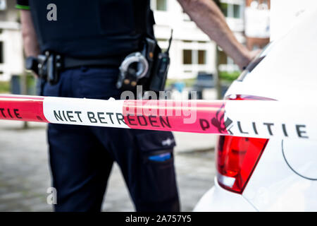 Der niederländische Polizist am Tatort in der Schule. Rote Schutzfolie Polizeioffizier, pistole, handschellen und Gewehr Riemen Stockfoto